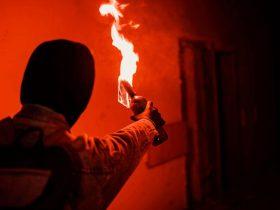 Mann wirftt eine entzündete Brandflasche